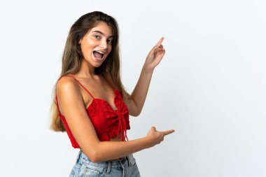 Beyaz arka planda izole edilmiş beyaz tenli genç bir kadın parmak göstererek bir ürün sunuyor.