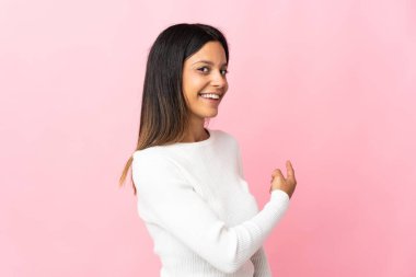 Pembe arka planda izole edilmiş beyaz kız geriye işaret ediyor.