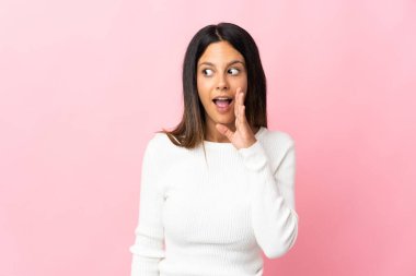 Pembe arka planda izole edilmiş beyaz bir kız. Yan tarafa bakarken sürpriz bir jest yapıyor.