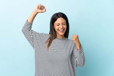 Mavi arka planda izole edilmiş beyaz kız zaferi kutluyor.