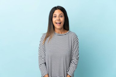 Mavi arka planda yalıtılmış beyaz bir kız. Sürpriz bir yüz ifadesi var.