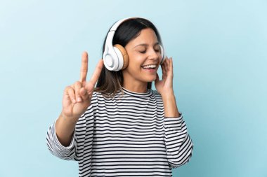 Beyaz kız mavi arka planda izole edilmiş müzik dinliyor ve şarkı söylüyor.