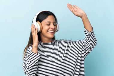 Beyaz kız mavi arka planda izole edilmiş müzik ve dans dinliyor.