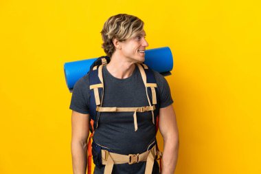 Genç dağcı, izole edilmiş sarı arka planda.