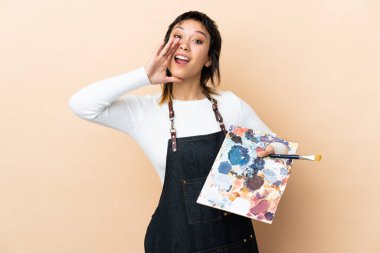 Arkaplanda palet tutan genç bir sanatçı ağzı açık bağırıyor.