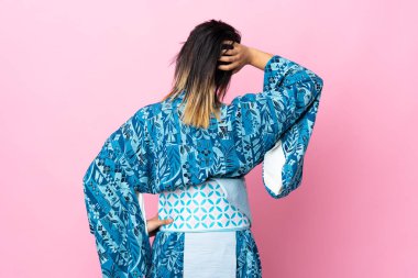 İzole edilmiş mavi arka planda kimono giyen genç bir kadın.