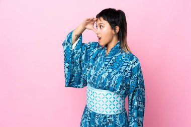 İzole edilmiş mavi arka plan üzerinde kimono giyen genç bir kadın.