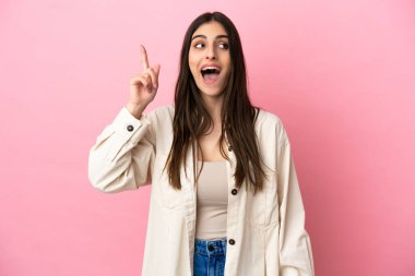 Pembe arka planda izole edilmiş genç beyaz kadın çözümü bulmak için parmağını kaldırıyor.