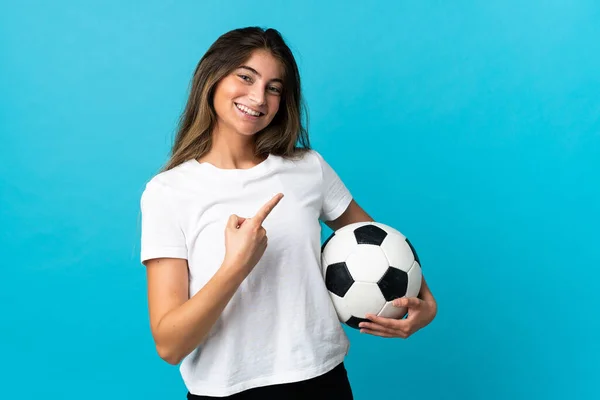 Młoda Kaukaska Kobieta Odizolowana Niebieskim Tle Piłką Nożną Wskazując Boczne — Zdjęcie stockowe
