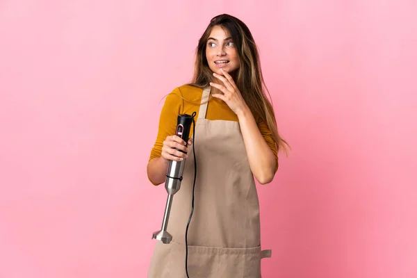 Jovem Chef Mulher Usando Liquidificador Mão Isolado Fundo Rosa Olhando — Fotografia de Stock