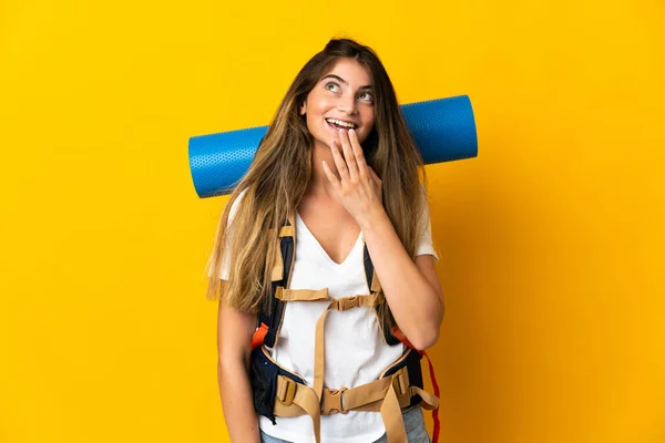若い登山家の女性は大きなバックパックを黄色の背景に隔離されながら笑顔を見上げ — ストック写真