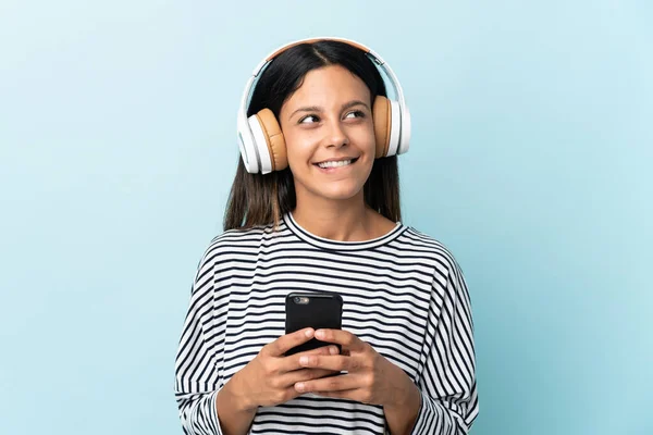 Caucásico Chica Aislado Azul Fondo Escuchar Música Con Móvil Pensando — Foto de Stock