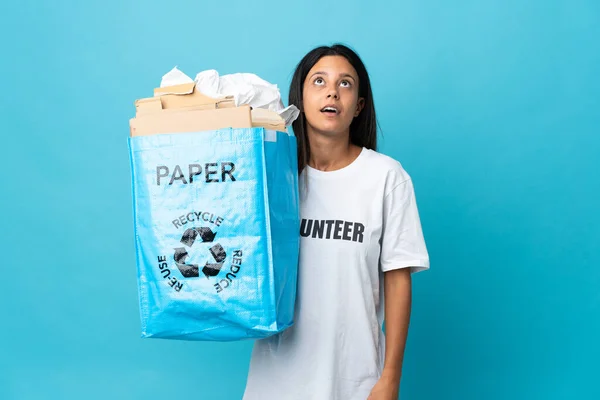年轻女子拿着一个装满了纸的回收袋 抬起头 满脸惊讶地看着 — 图库照片