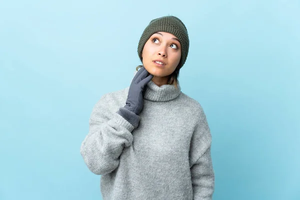 Jovem Uruguaia Com Chapéu Inverno Isolado Fundo Azul Pensando Uma — Fotografia de Stock