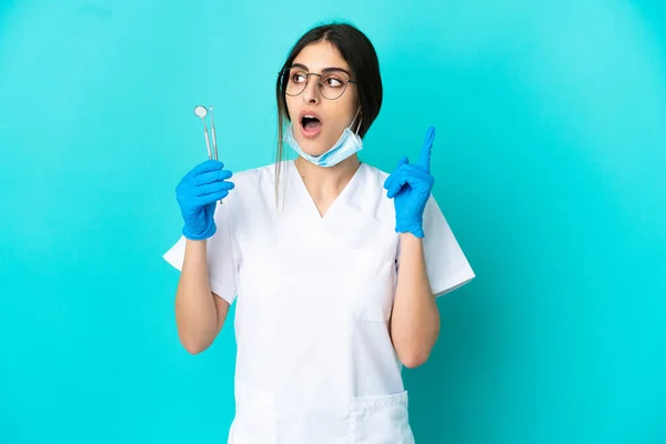 Junge Kaukasische Zahnärztin Die Werkzeuge Isoliert Auf Blauem Hintergrund Hält — Stockfoto