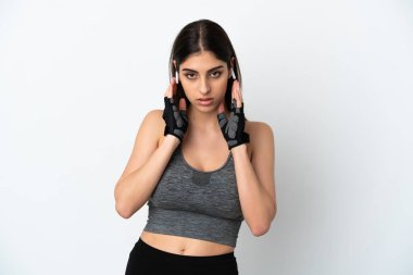 Beyaz arka planda izole edilmiş genç beyaz bir kadın müzik dinliyor ve ön tarafa bakıyor.