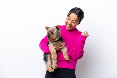 Beyaz arka planda izole edilmiş köpeği tutan genç İspanyol kadın zaferi kutluyor.