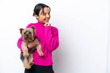 Beyaz arka planda izole edilmiş bir köpeği tutan genç İspanyol kadın bir fikir üretiyor ve ona bakıyor.