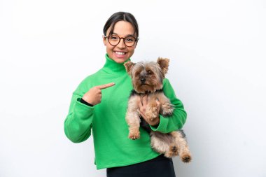 Beyaz arka planda izole edilmiş bir köpeği tutan genç İspanyol kadın.