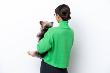 Beyaz arka planda izole edilmiş bir köpeği tutan genç İspanyol kadın.