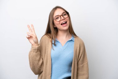 Beyaz arka planda izole edilmiş genç Litvanyalı kadın gülümsüyor ve zafer işareti gösteriyor.