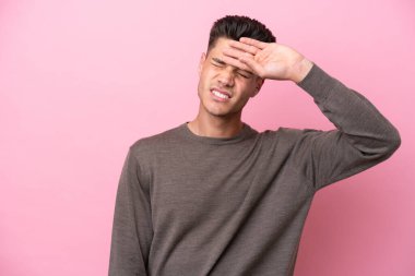 Pembe arka planda izole edilmiş, yorgun ve hasta bir ifadeyle genç beyaz bir adam.