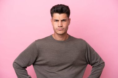 Kafkasyalı genç adam pembe arka planda izole edilmiş kızgın.