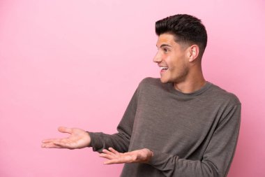 Pembe arka planda mahsur kalmış beyaz bir genç. Sürpriz bir ifadeyle yan tarafa bakıyor.