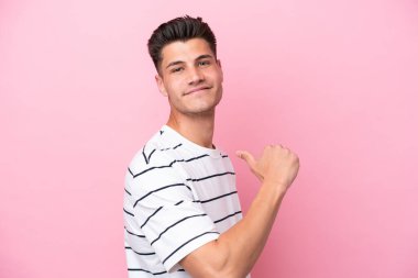 Genç beyaz adam pembe arka planda soyutlanmış gururlu ve kendini beğenmiş.