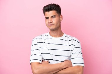 Mutsuz bir ifadeyle pembe arka planda izole edilmiş genç beyaz bir adam.