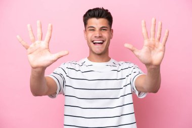 Pembe arka planda izole edilmiş genç beyaz adam parmaklarıyla ona kadar sayıyor.