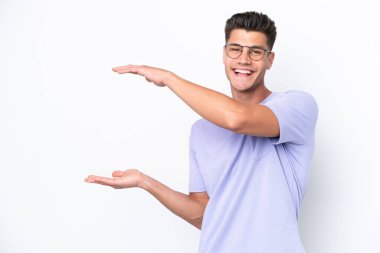 Beyaz arka planda izole edilmiş genç beyaz bir adam ilan vermek için kopyalama alanı tutuyor.