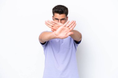 Beyaz arka planda izole edilmiş genç beyaz bir adam bir eylemi durdurmak için eliyle jesti durduruyor.