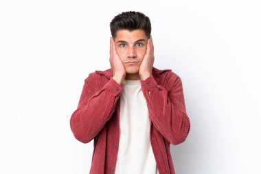 Beyaz arka planda izole edilmiş genç beyaz adam hayal kırıklığına uğramış ve kulaklarını kapatmış.