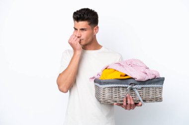 Çamaşır sepetini tutan beyaz arka planda izole edilmiş genç beyaz bir adam şüpheleri var.