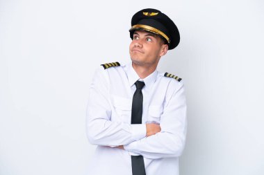 Beyaz arka planda izole edilmiş beyaz bir uçak pilotu omuzlarını kaldırırken şüpheli hareketlerde bulunuyor.