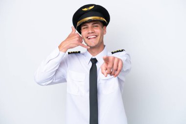 Kafkasyalı uçak pilotu beyaz arka planda izole edilmiş, telefon jesti yapıyor ve ön tarafı işaret ediyor.