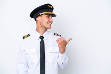 Beyaz arka planda izole edilmiş Kafkasyalı uçak pilotu bir ürün sunmak için kenarı işaret ediyor