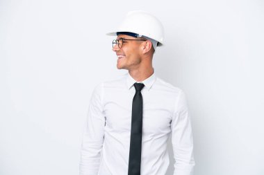 Miğferli ve elinde beyaz arka planda izole edilmiş planları olan beyaz bir mimar.