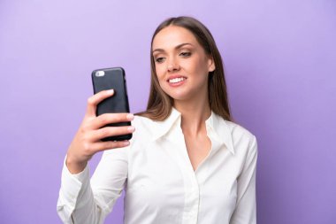 Mor arka planda izole edilmiş beyaz bir kadın selfie çekiyor.