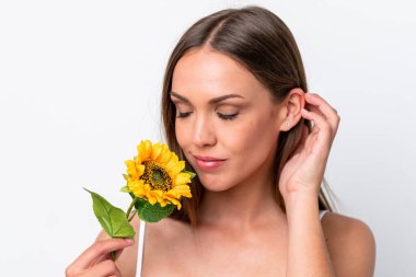 Beyaz arka planda izole edilmiş beyaz bir kadın elinde bir ayçiçeği tutuyor. Portreyi kapat