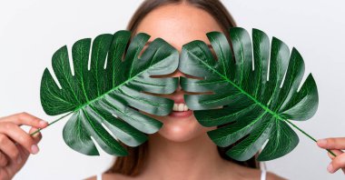 Beyaz arka planda izole edilmiş beyaz bir kadın elinde mutlu bir ifadeyle bir palmiye yaprağı tutuyor. Portreyi kapat