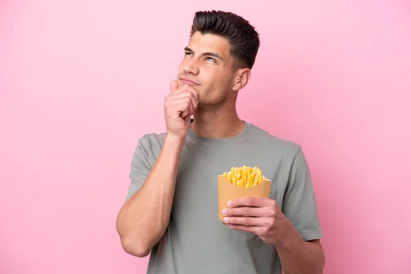 Joven Caucásico Hombre Celebración Frito Chips Aislado Rosa Fondo Teniendo —  Fotos de Stock