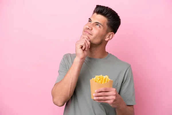 Jonge Blanke Man Met Gebakken Chips Geïsoleerd Roze Achtergrond Zoek — Stockfoto