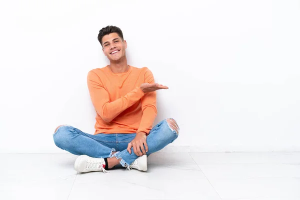 Mladý Muž Sedící Podlaze Izolovaný Bílém Pozadí Představuje Nápad Usmívá — Stock fotografie