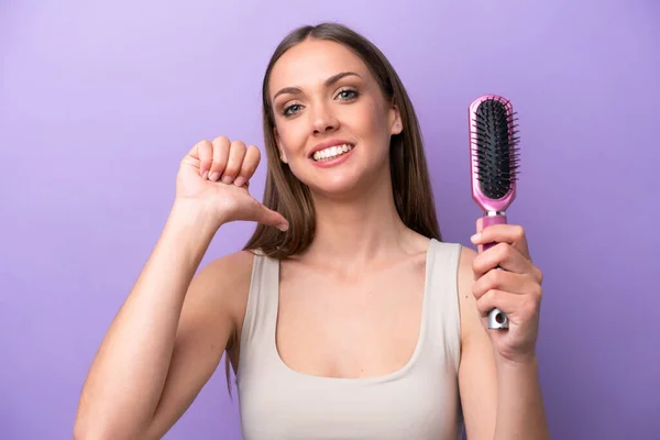 Joven Mujer Caucásica Sosteniendo Cepillo Aislado Sobre Fondo Púrpura Orgulloso —  Fotos de Stock