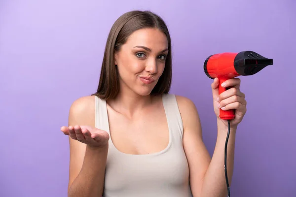 Joven Mujer Caucásica Sosteniendo Secador Pelo Aislado Sobre Fondo Púrpura —  Fotos de Stock