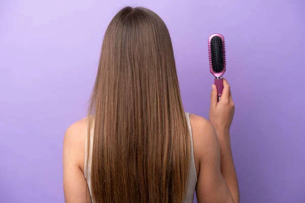 Young Caucasian Woman Holding Hairbrush Isolated Purple Background Back Position — Stock Photo, Image