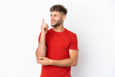 Beyaz arka planda izole edilmiş beyaz, yakışıklı genç bir adam harika bir fikre işaret ediyor.