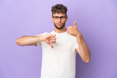 Mor arka planda izole edilmiş beyaz bir adam iyi-kötü işareti yapıyor. Evet ya da hayır arasında kararsız